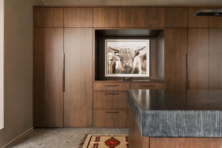 Integrated wood-panel cabinetry with recessed hardware, complemented by a large island featuring a fluted stone countertop
