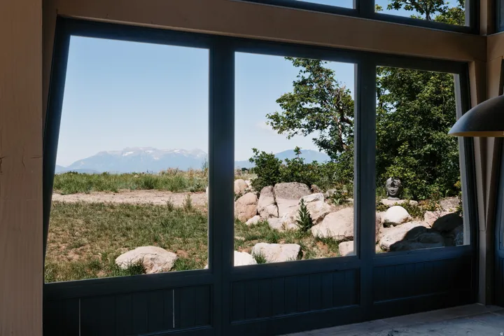 Expansive multi-pane windows with dark frames, offering mountain and natural landscape scenery