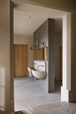 Dual basin vanity featuring stone trough sinks and matte black wall-mounted faucets