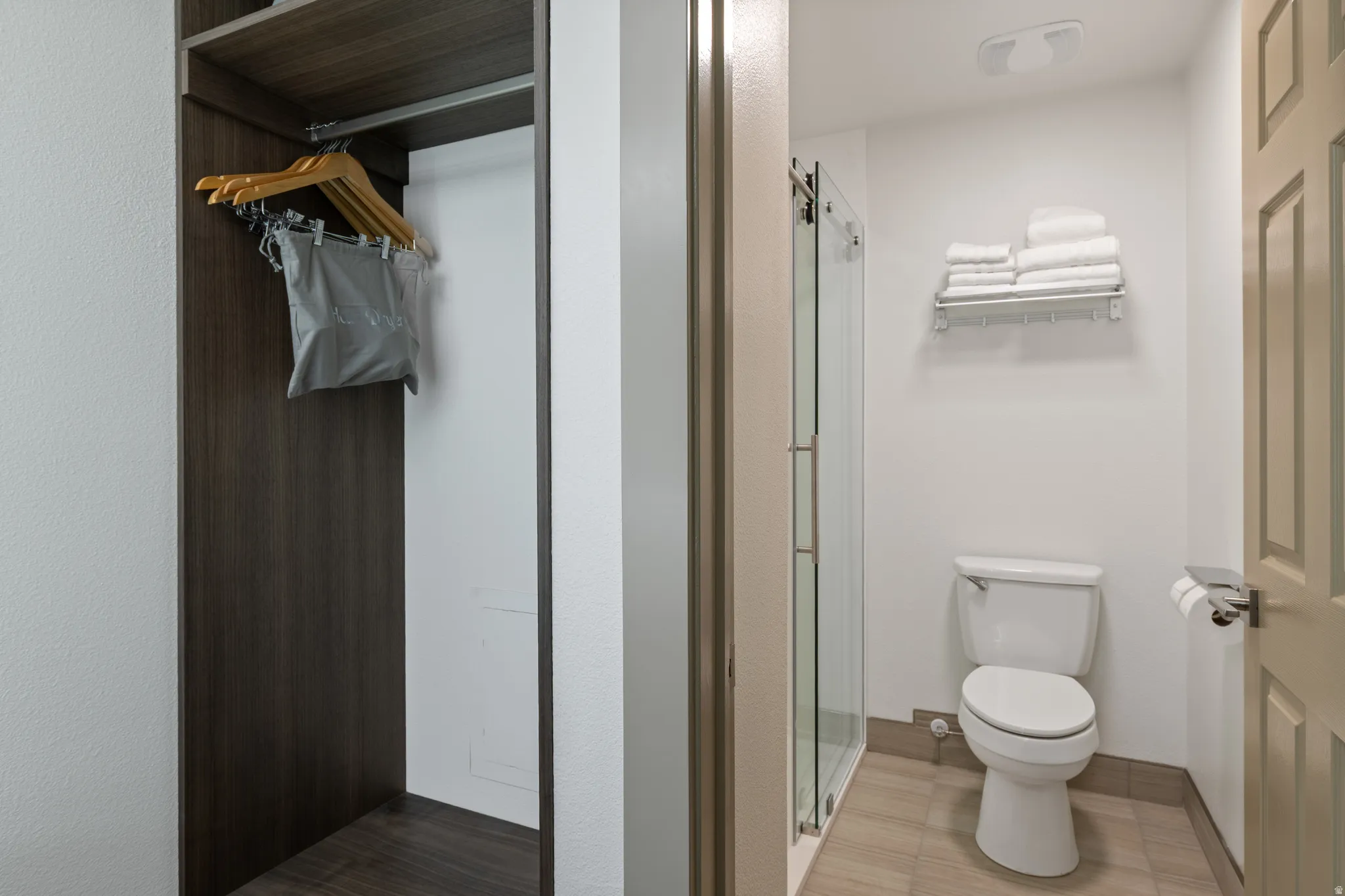 Compact bathroom featuring a glass-enclosed shower, white toilet, and tile flooring