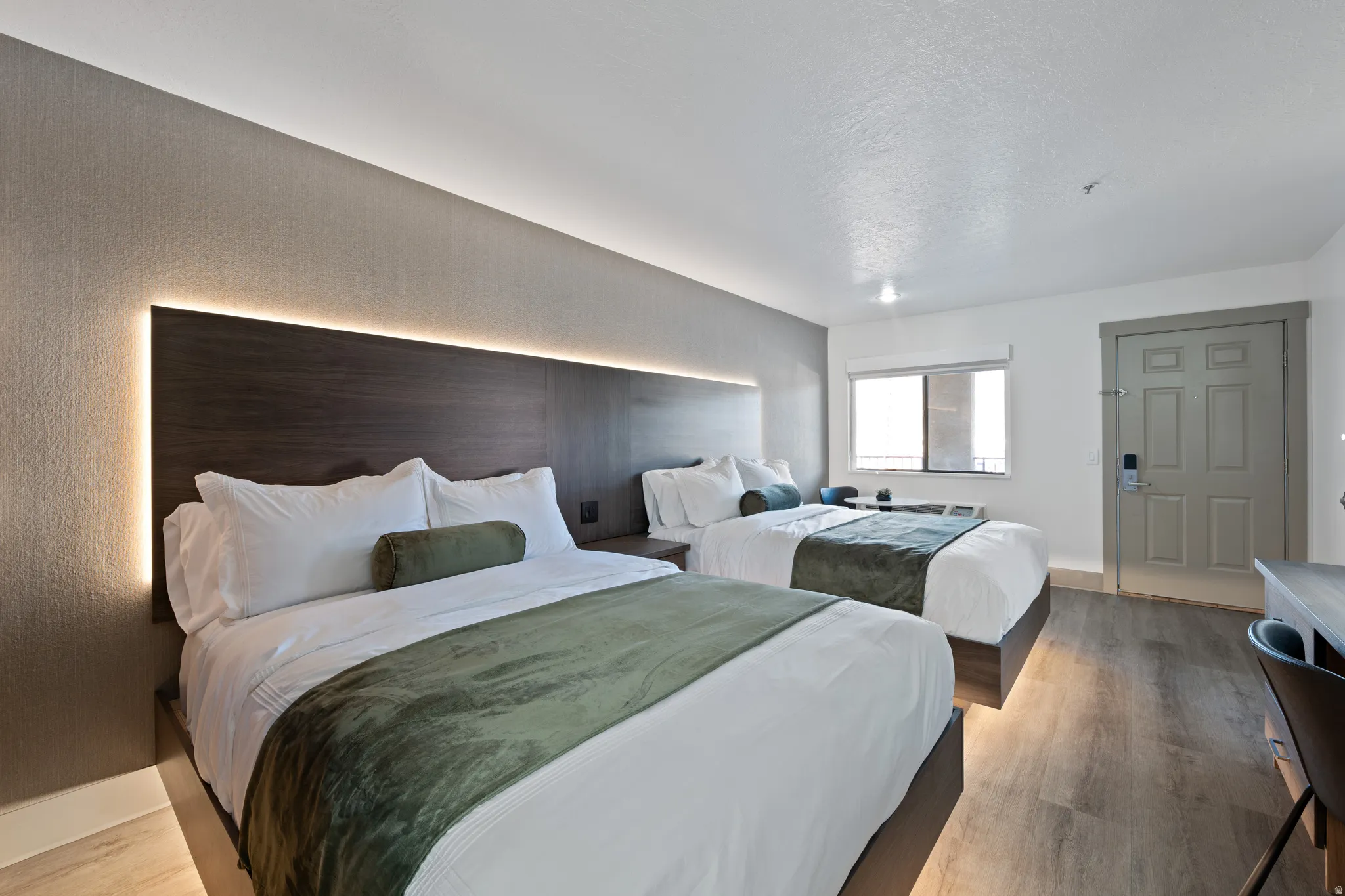 Spacious bedroom featuring wood-finish flooring and two queen-sized beds