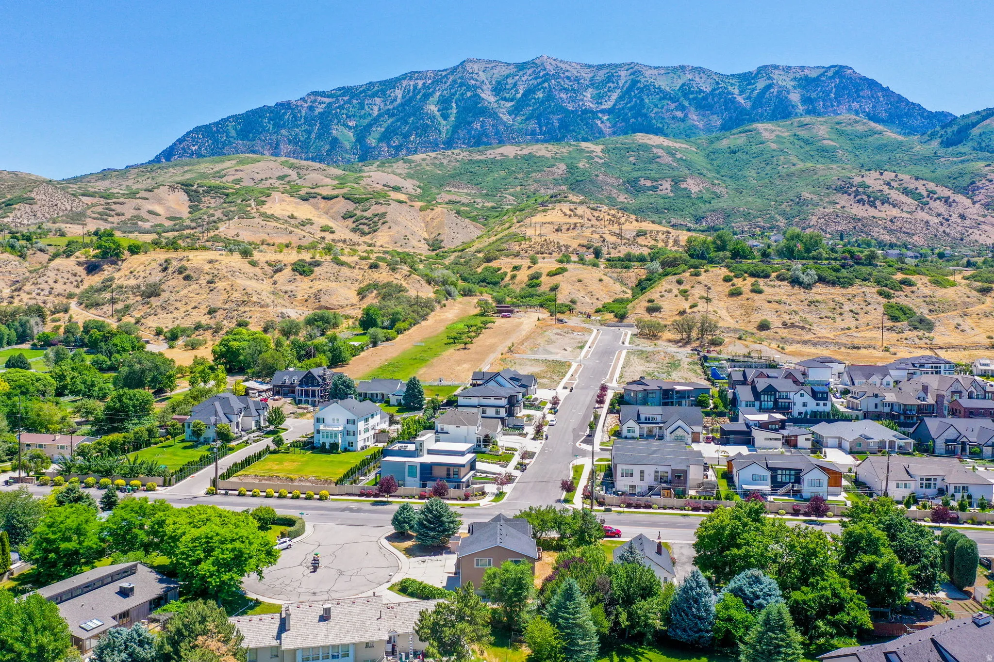 Expansive mountain range backdrop framing a residential area with diverse architectural styles, including contemporary and traditional designs