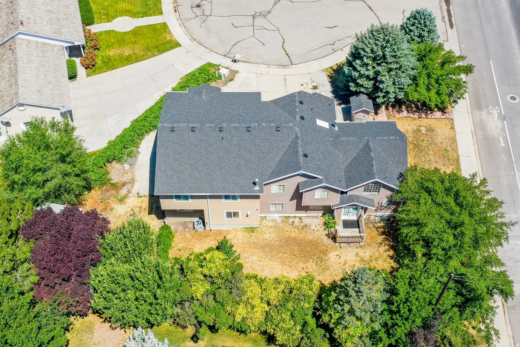 Multi-level residence featuring a gray shingle roof and a light brown siding exterior