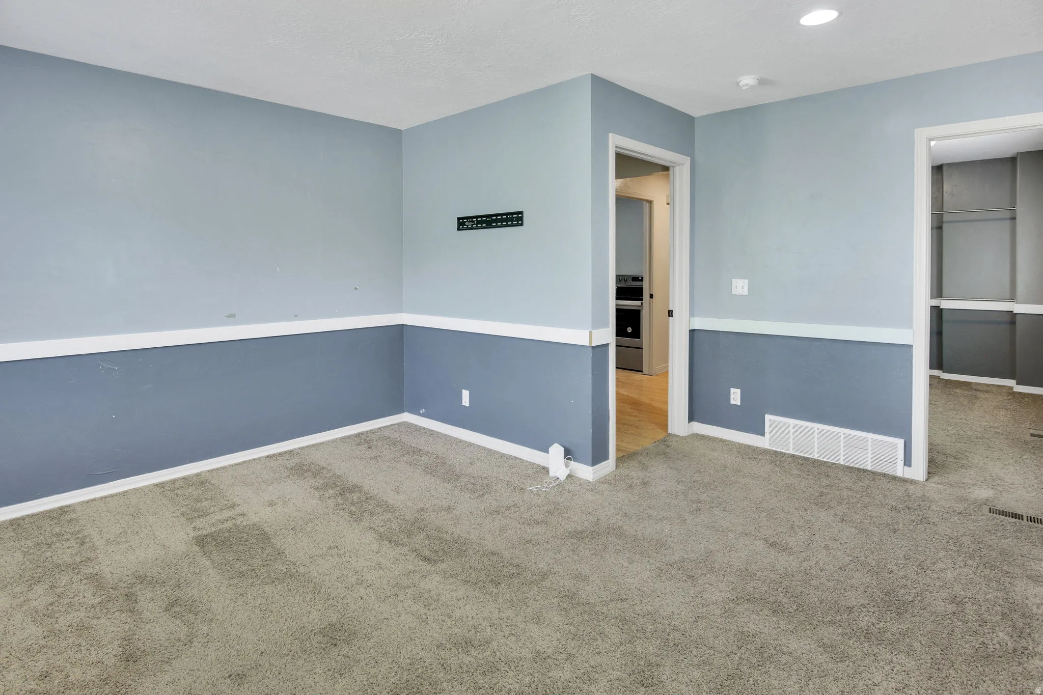 Carpeted interior space featuring two-tone wall treatment with chair rail molding