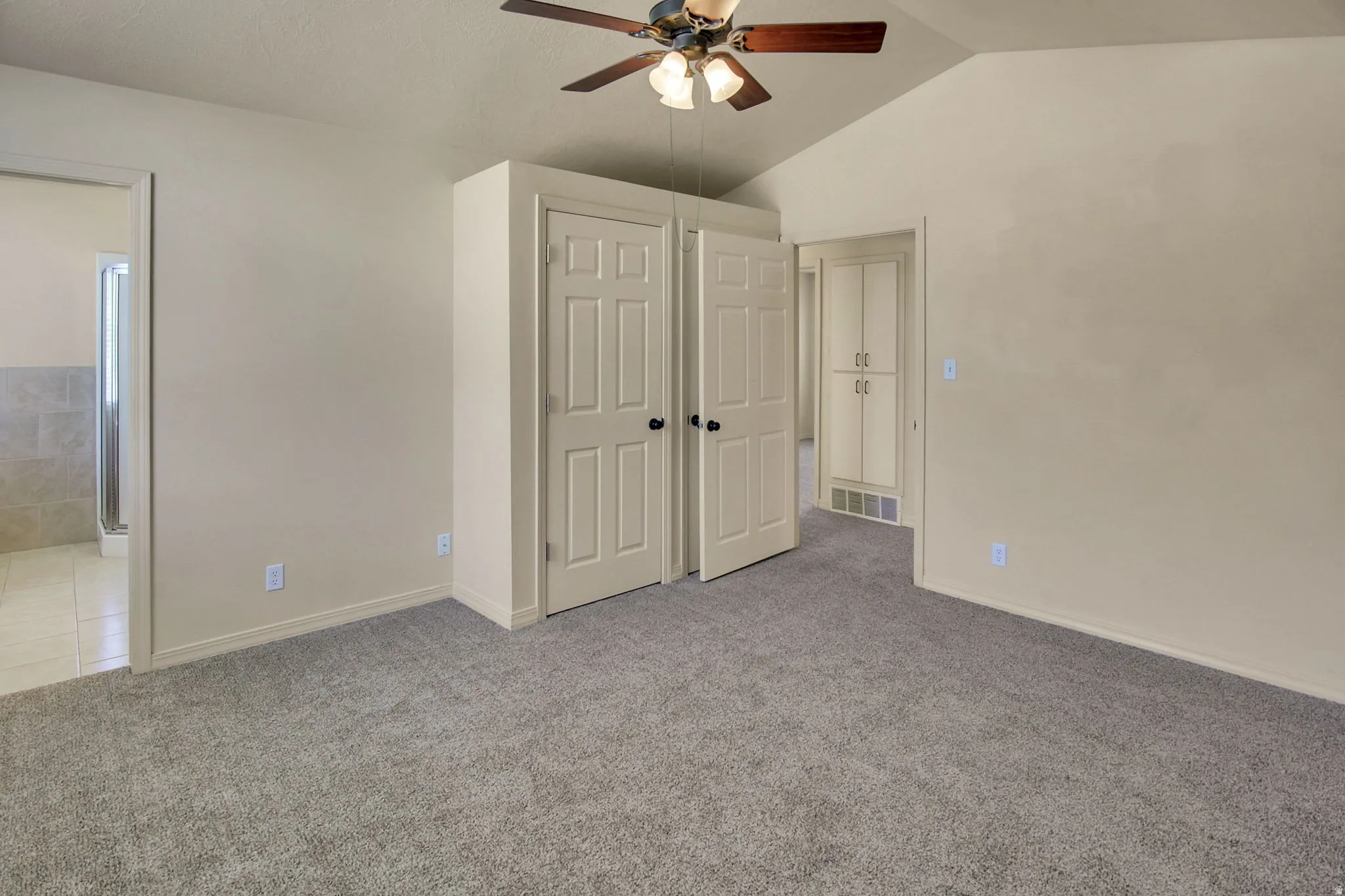 Carpeted room featuring a vaulted ceiling and a ceiling fan with integrated lighting