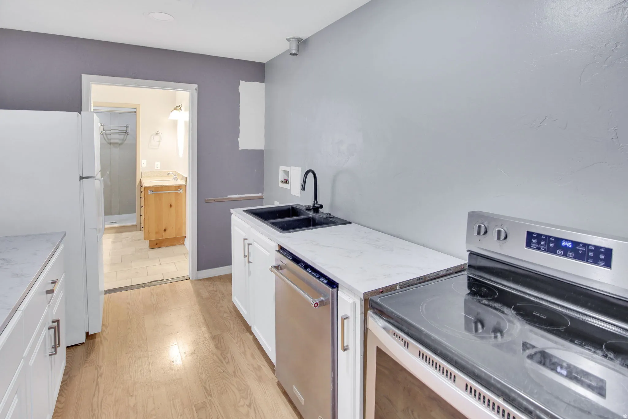 Kitchen space featuring wood-finish flooring, white cabinetry, and light-toned countertops
