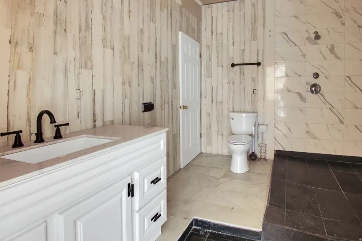 Bathroom featuring a white vanity with a rectangular undermount sink, a light-toned countertop, and matte black fixtures
