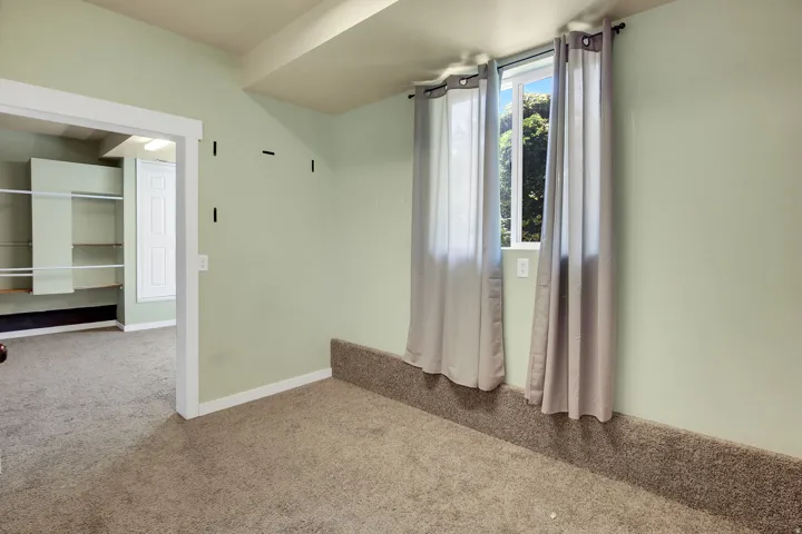 Carpeted room with light green walls and a single window