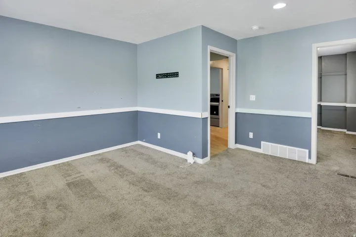 Carpeted interior space featuring two-tone wall treatment with chair rail molding