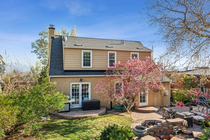 Rear exterior featuring a multi-level patio, brick fire pit, and mature landscaping