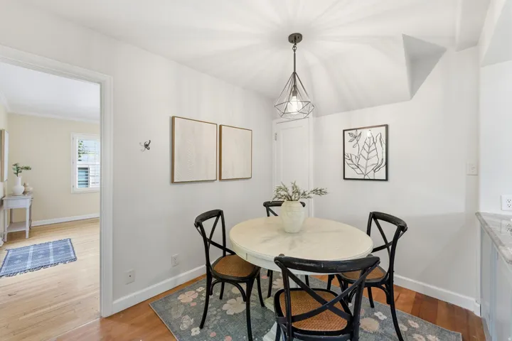 Dining area featuring wood-finish flooring, a contemporary pendant light fixture, and crown molding