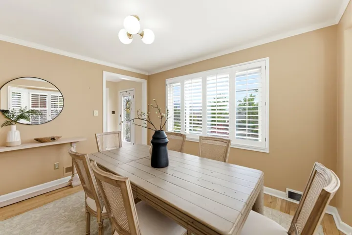 Dining area featuring light wood-finish flooring, crown molding, and a three-light ceiling fixture