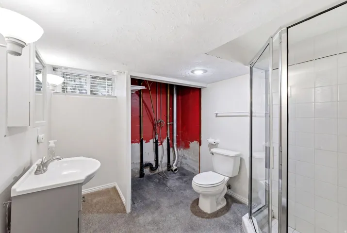 Bathroom featuring a corner vanity with integrated sink, a glass-enclosed shower with white tiled walls, and a window with horizontal blinds