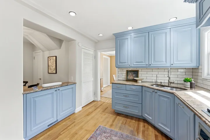 Kitchen featuring light blue cabinetry, natural wood-finish flooring, recessed lighting, and subway tile backsplash