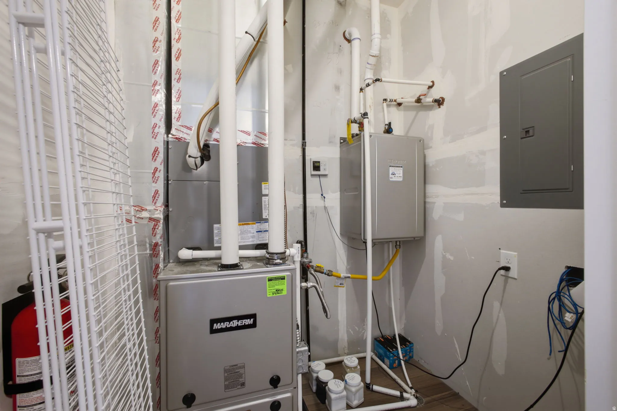 Utility area featuring a furnace, tankless water heater, and electrical panel