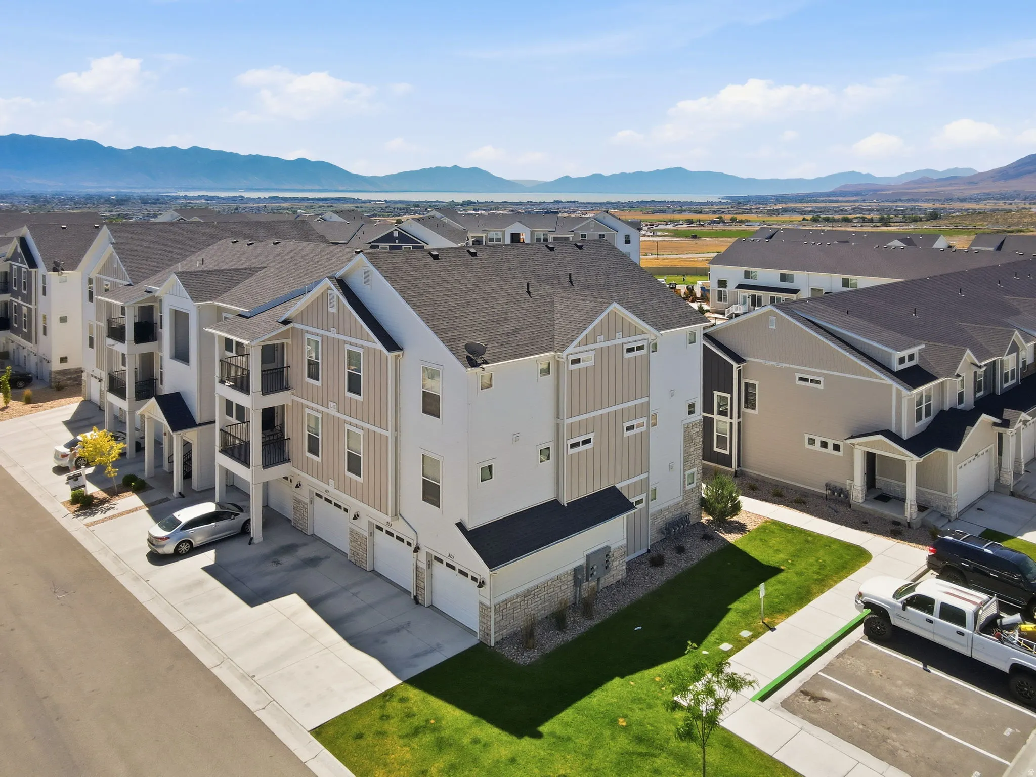 Multi-level building featuring a combination of light-toned siding, dark roofing, and stone accents