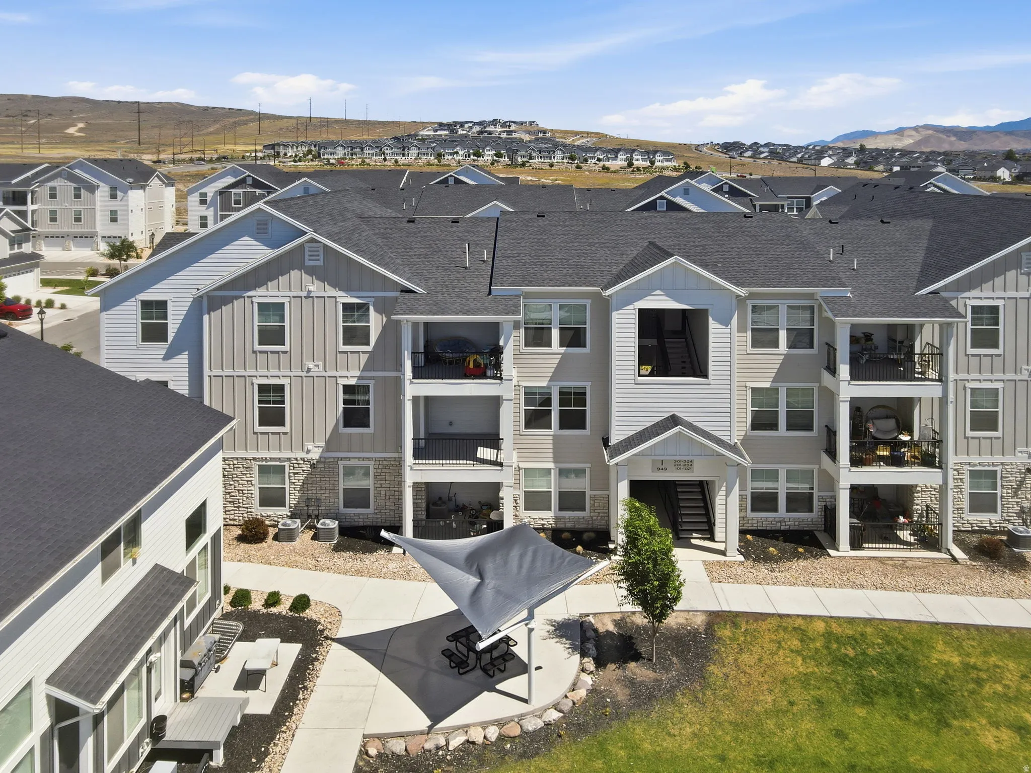 Multi-story residential building featuring light-colored siding and stone-finish accents