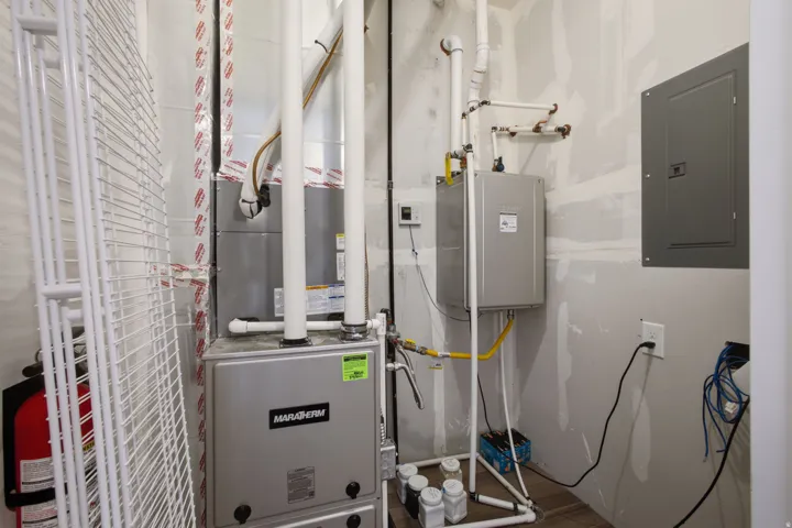 Utility area featuring a furnace, tankless water heater, and electrical panel
