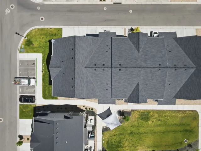 Modern townhome development featuring dark gray composite shingle roofing and light concrete sidewalks
