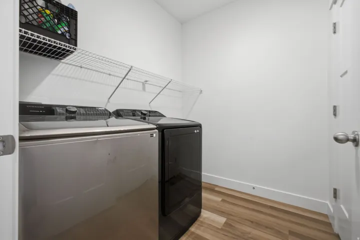 Dedicated laundry area featuring wood-finish flooring, white walls, and built-in wire shelving