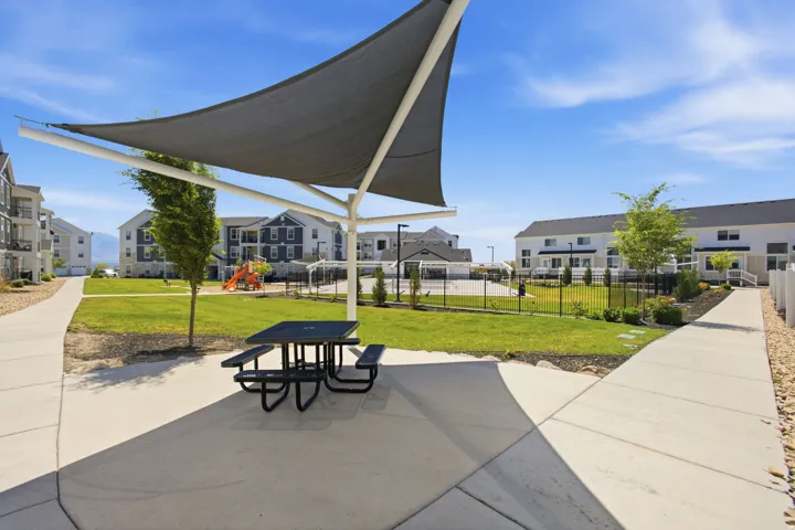 Outdoor picnic area featuring a shade structure and a black picnic table with benches