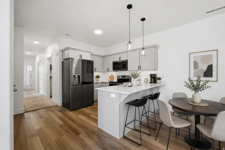 Open-concept kitchen featuring light gray cabinetry, built-in microwave, and a breakfast bar with pendant lighting