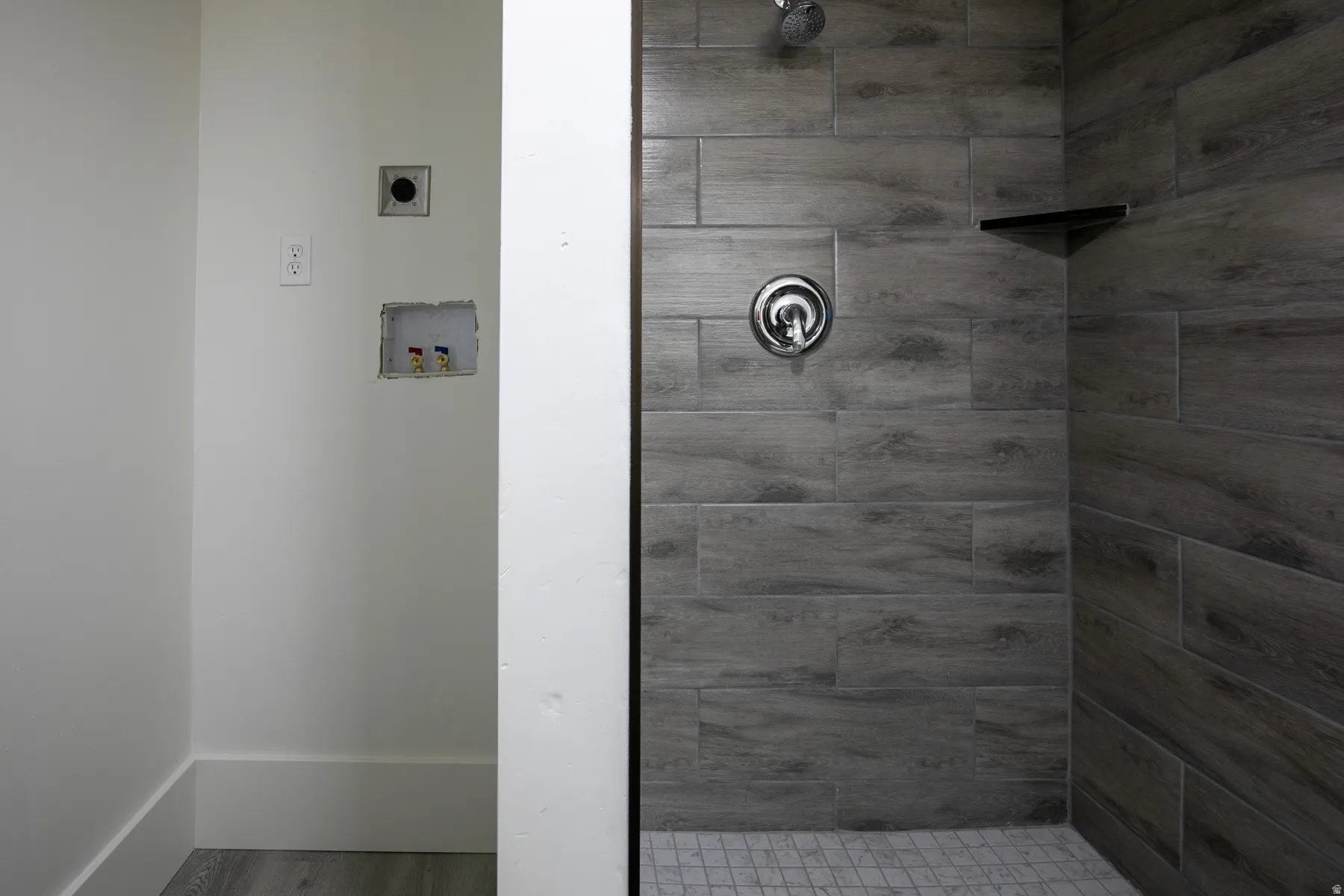 Bathroom featuring wood-finish tile shower walls, a mosaic tile shower floor, and a built-in shower shelf