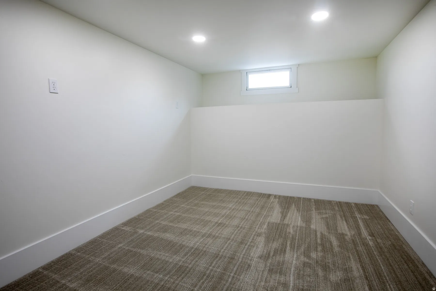 Interior room featuring recessed lighting, a window, white walls, white baseboards, and patterned carpeting