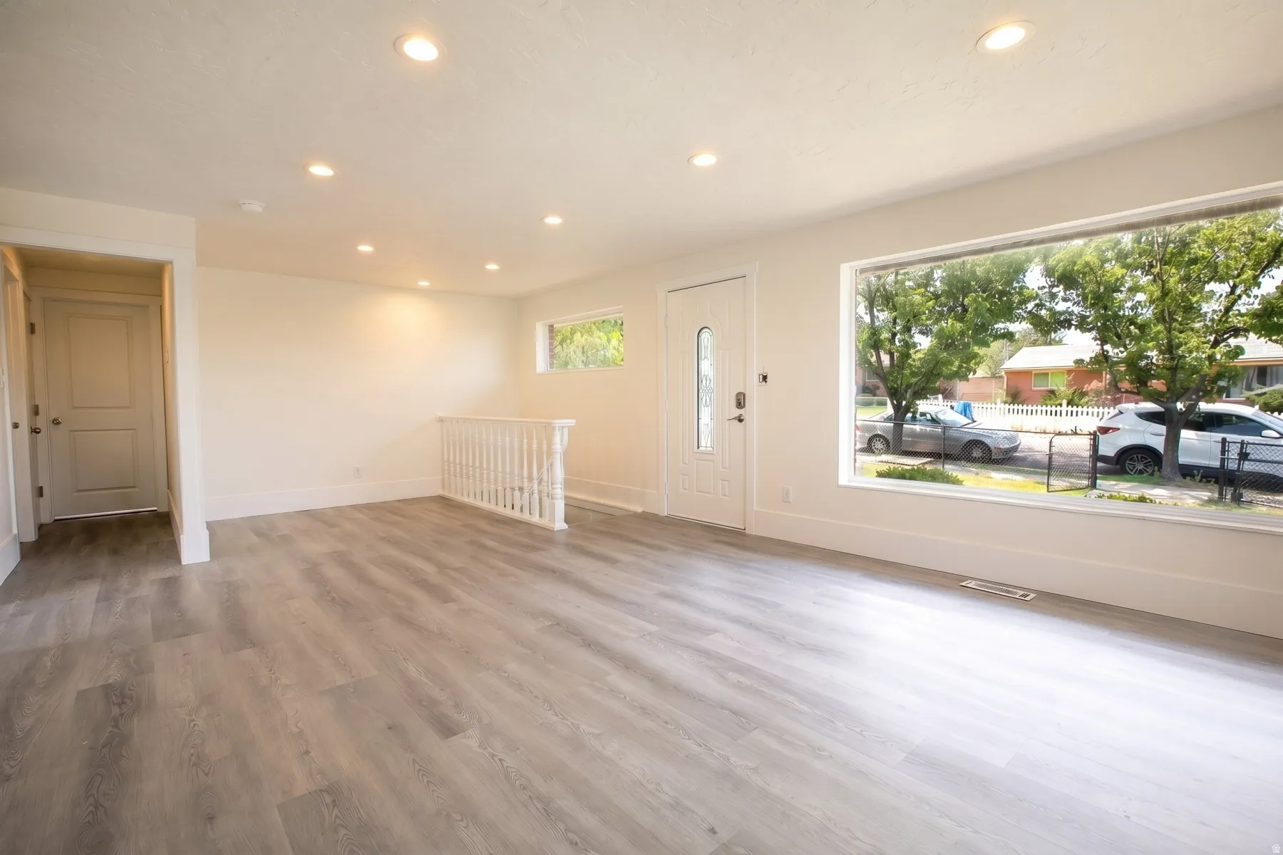 Spacious living area featuring contemporary wood-finish flooring, recessed lighting, and a large picture window