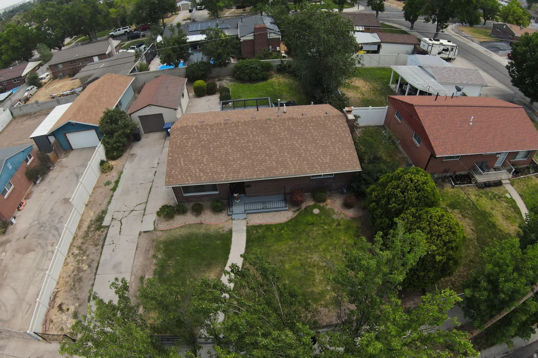 Single-family residence featuring a brown shingle roof, a front porch with railing, and a mature treed front yard