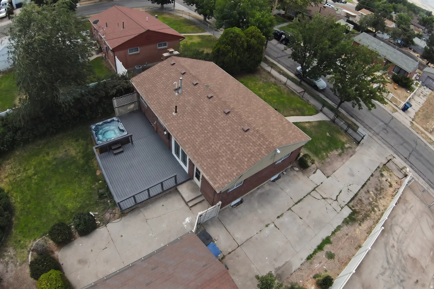 Rear exterior featuring a spacious composite deck with integrated hot tub, brick siding, and a gabled roof