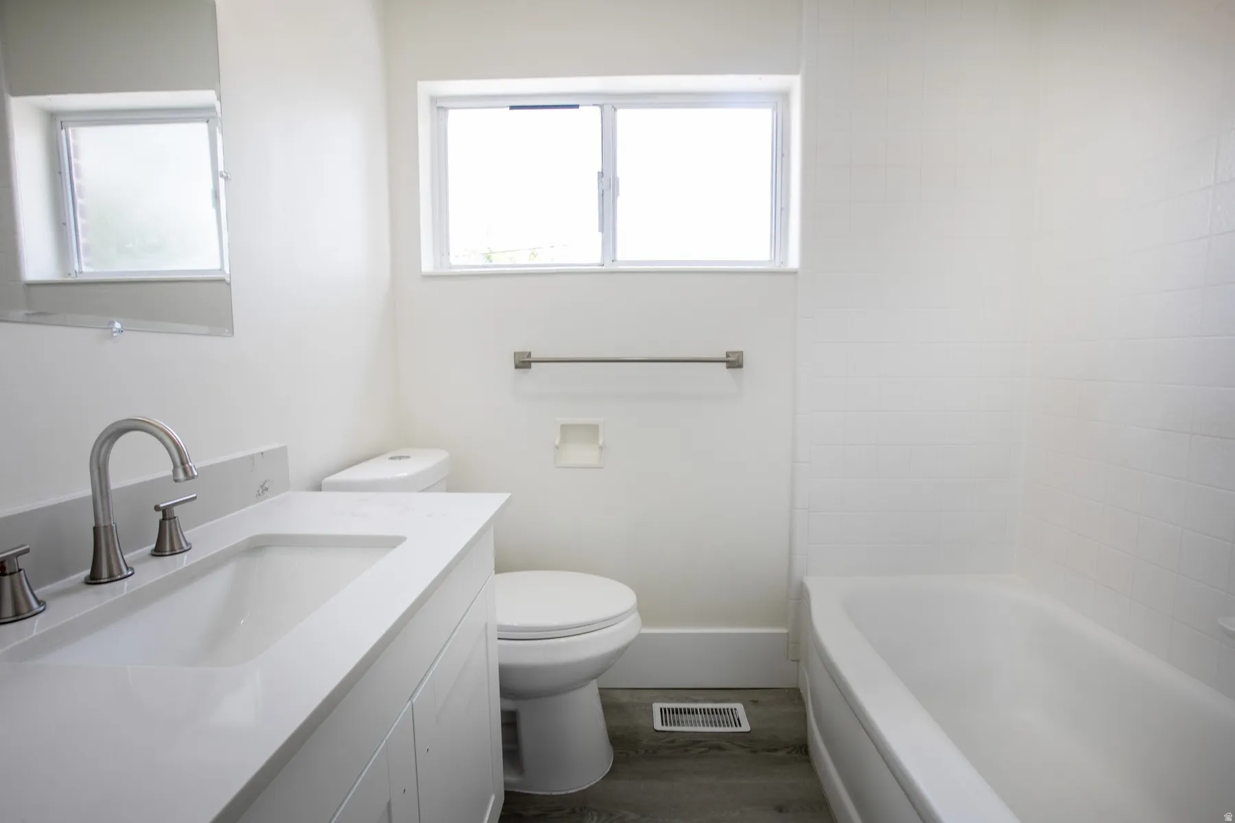 Bathroom featuring a white vanity with an integrated sink, brushed nickel faucet, and a quartz countertop