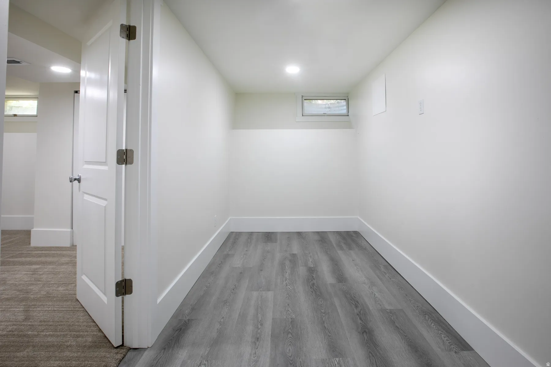 Interior room featuring light gray wood-finish flooring, white painted walls, and white baseboards