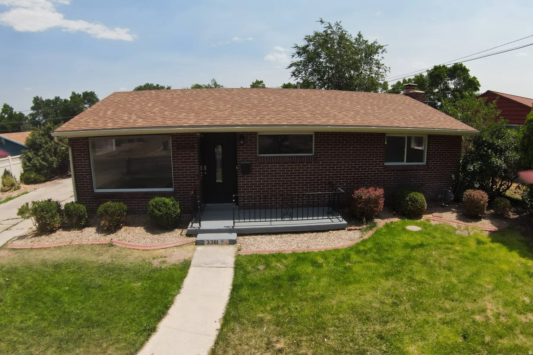 Brick exterior featuring a brown shingle roof and a prominent picture window