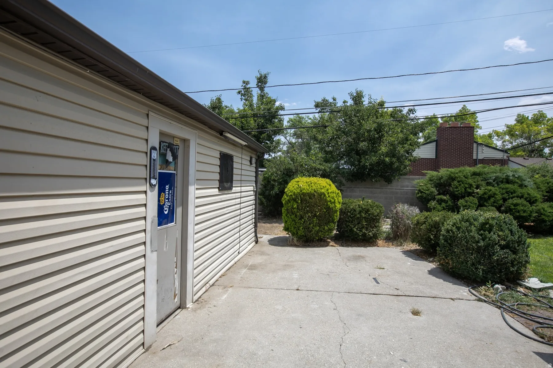 Siding exterior structure with a flat roofline, concrete patio, and mature landscaping