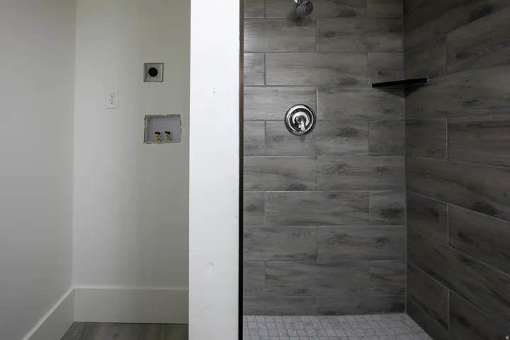Bathroom featuring wood-finish tile shower walls, a mosaic tile shower floor, and a built-in shower shelf