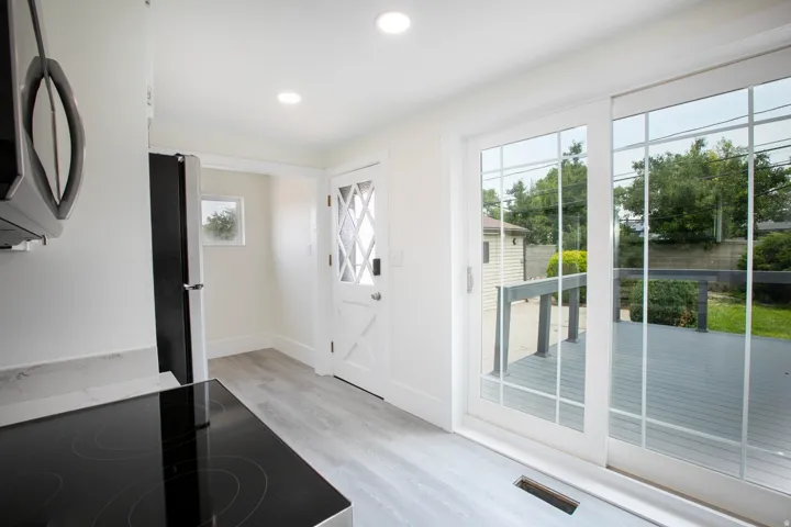 Light-filled interior featuring a black electric cooktop, light wood-finish flooring, and recessed ceiling lighting