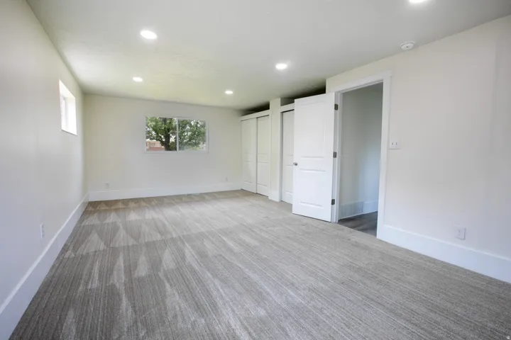 Expansive room featuring a window, modern recessed lighting, white trim, and light-toned patterned carpet