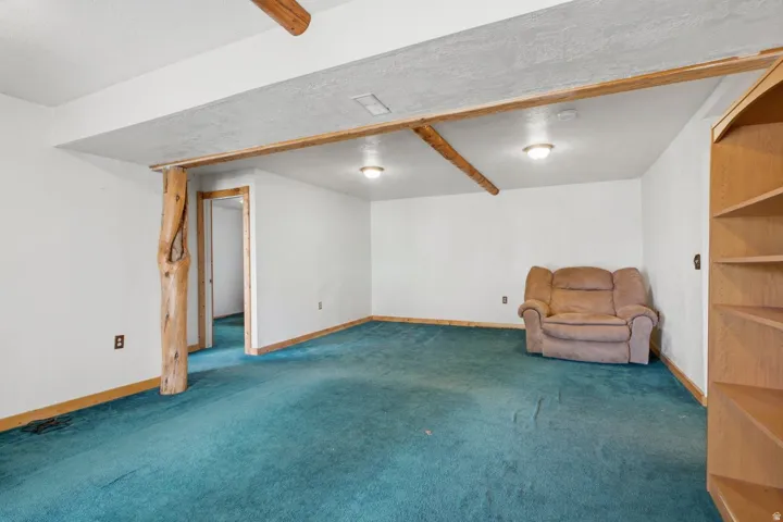 Recessed lighting illuminating the space, natural wood-finish trim, built-in shelving, and a prominent wood-finish structural beam