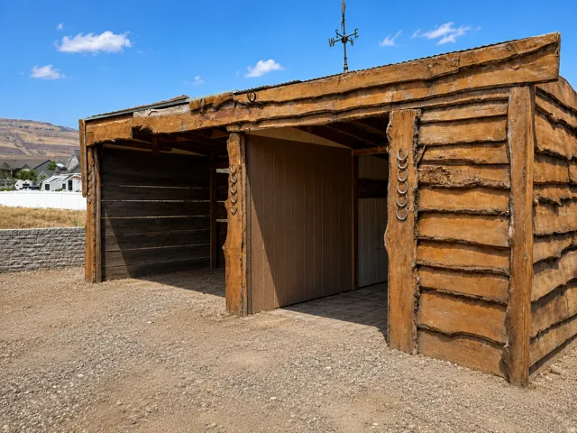 Rustic outdoor structure featuring rough-hewn timber siding and a corrugated metal roof