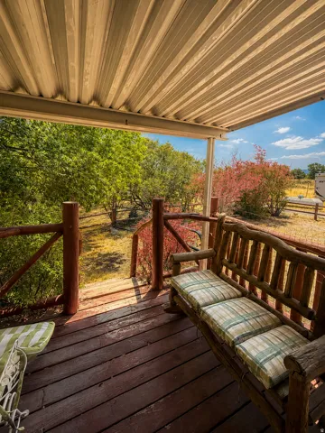 Covered porch featuring wood plank flooring, a rustic wood railing, and a corrugated metal ceiling