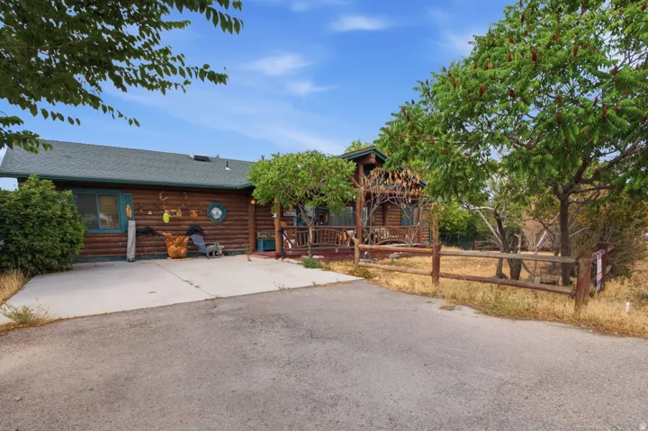 Log cabin exterior with a green shingle roof, covered front porch, and a concrete driveway