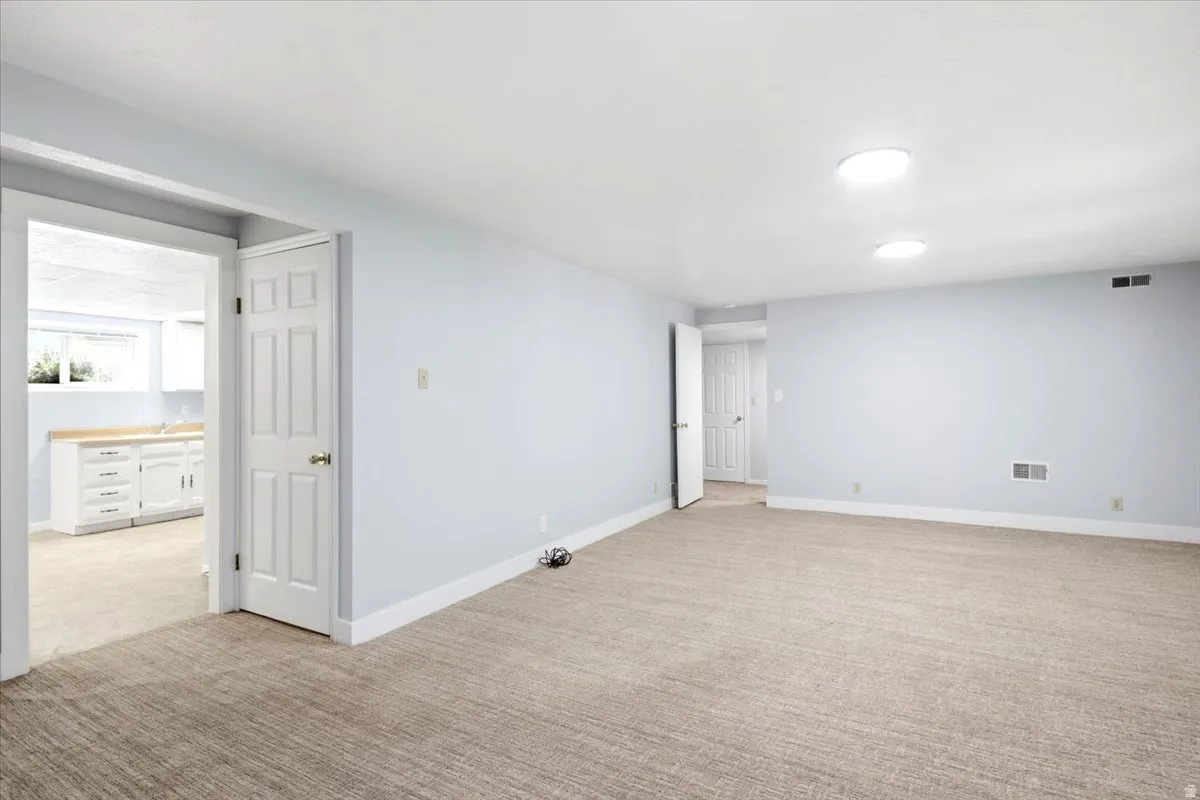 Spacious interior room with light-colored walls and carpeted flooring