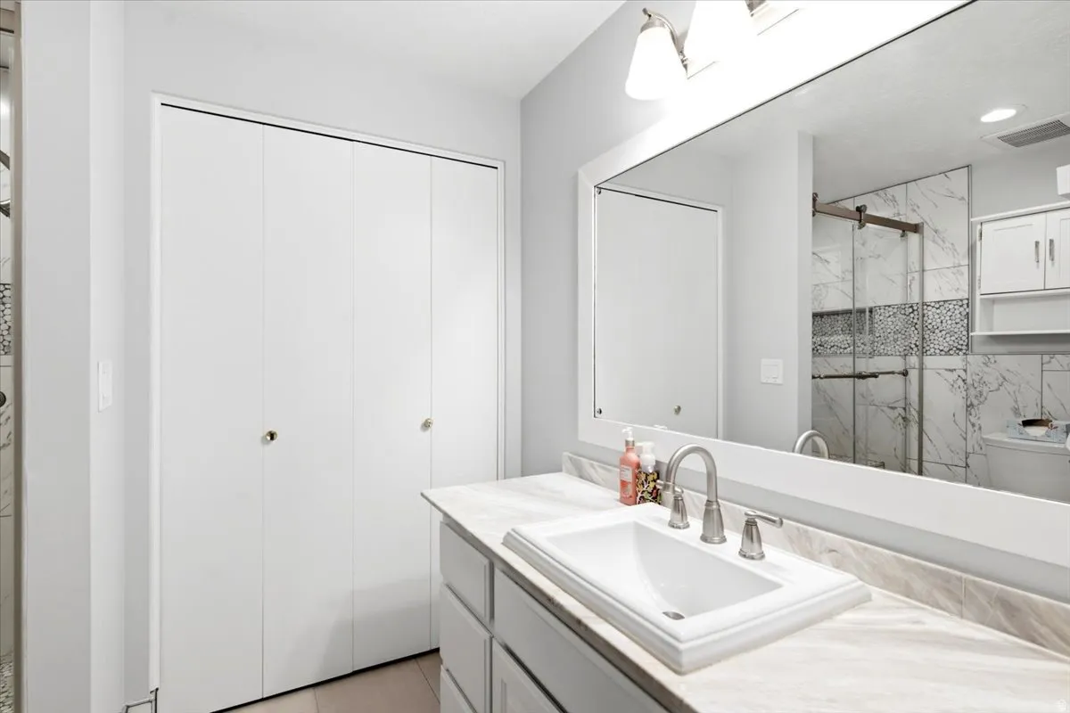 Bathroom vanity featuring a rectangular undermount sink, brushed nickel faucet, and a light-toned countertop
