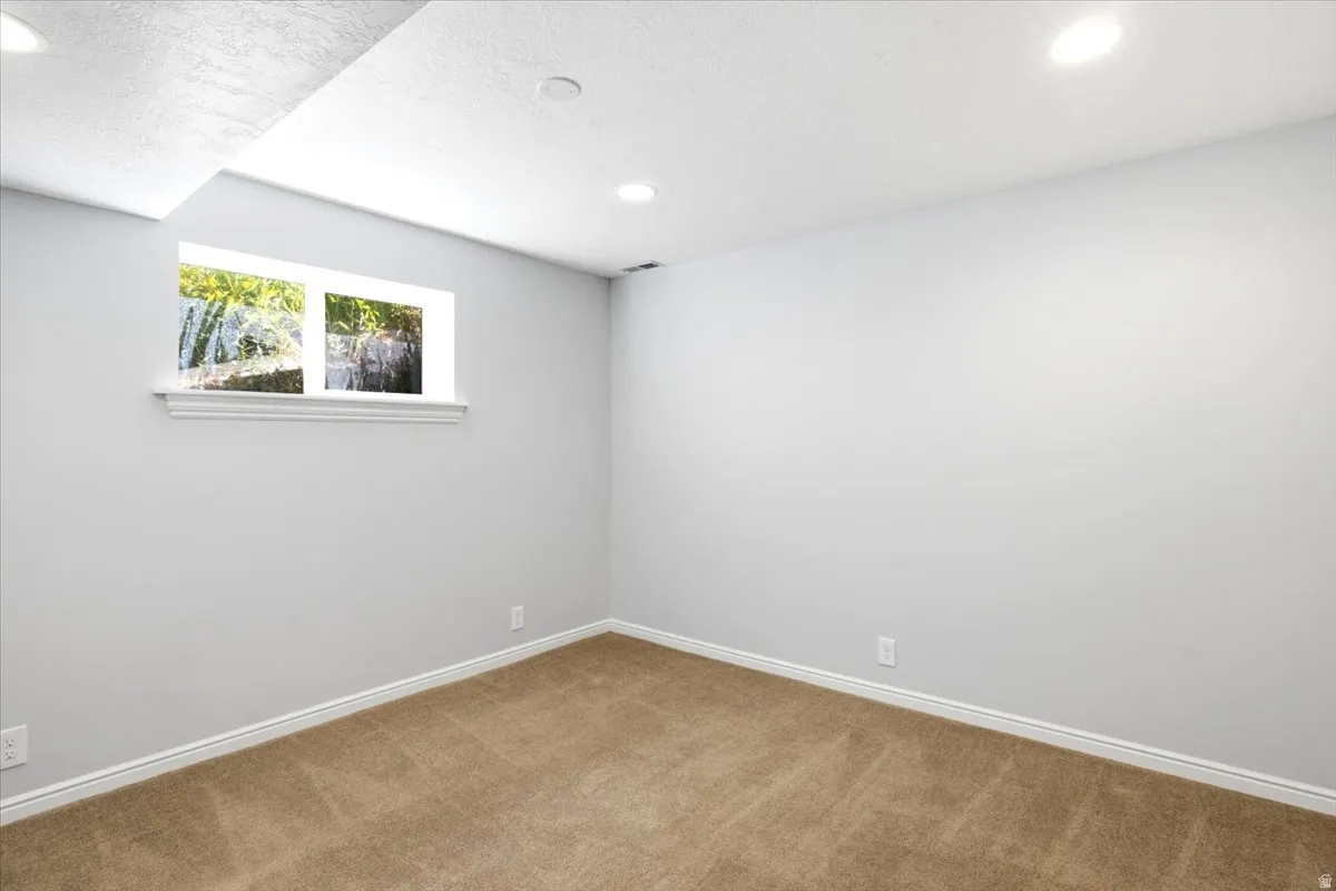 Carpeted room featuring a white-trimmed window, recessed lighting, and light gray walls with white baseboards