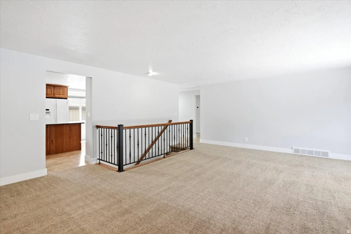Open-concept living area with neutral carpeting and light-toned walls