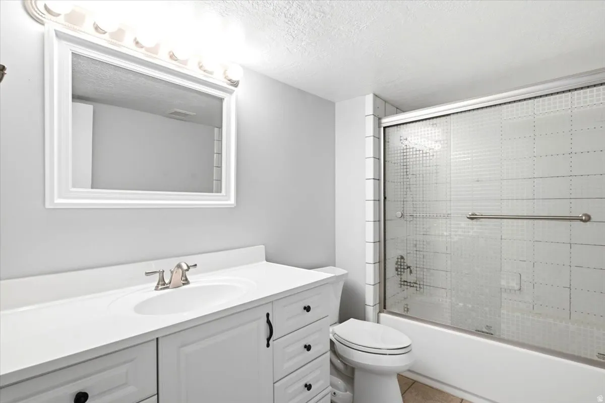 Bathroom featuring a white vanity with integrated sink, brushed nickel faucet, framed mirror, and overhead vanity lighting