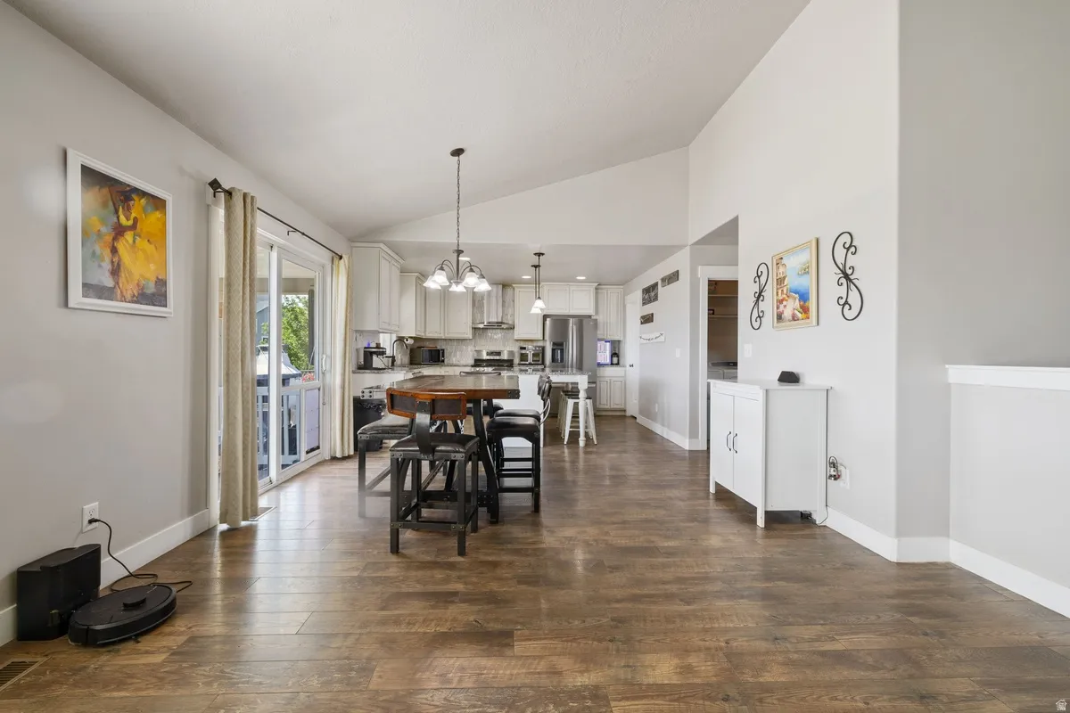 Expansive open-concept living space with vaulted ceilings, wood-finish flooring, and light gray walls