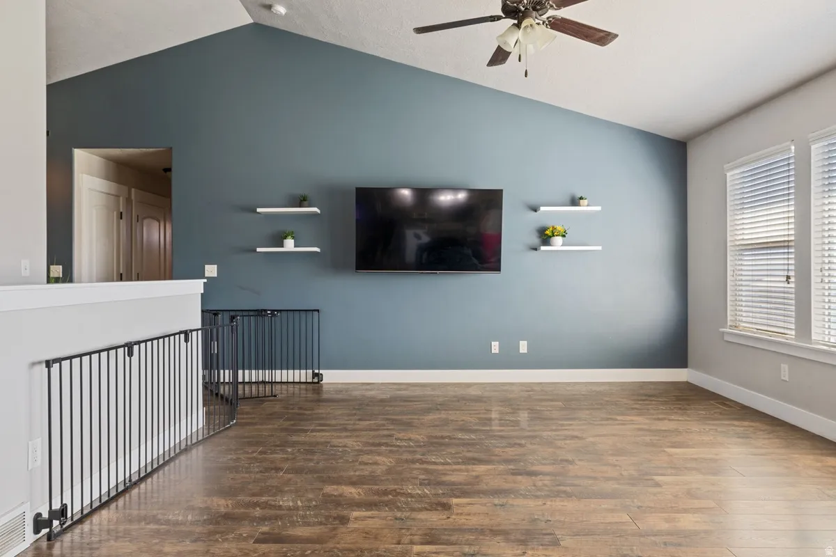 Vaulted ceilings complement the accent wall, featuring wood-finish flooring throughout the space