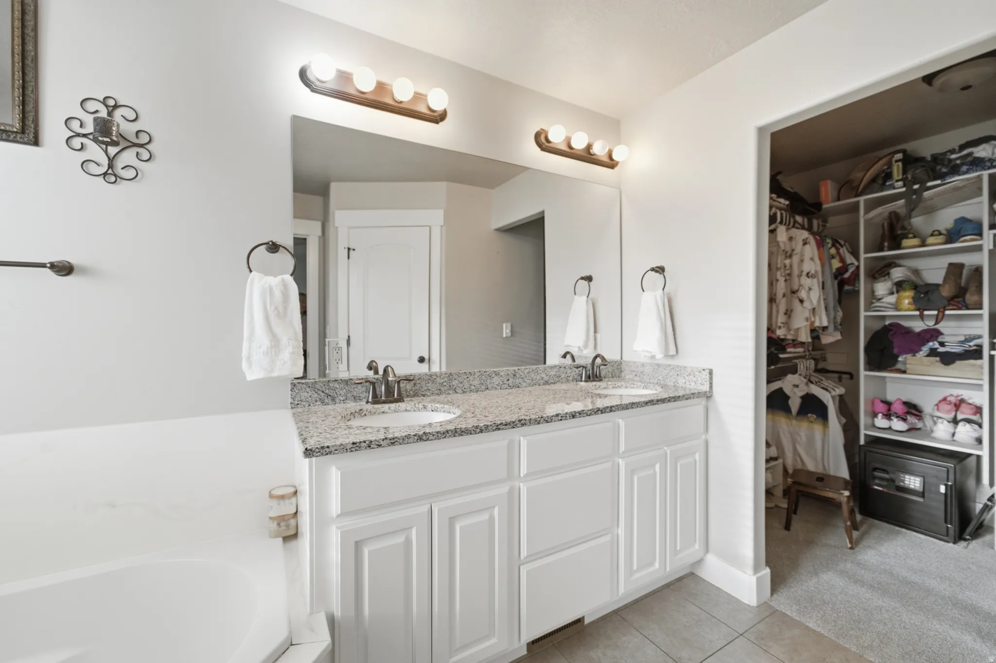 Dual vanity with granite-style countertop, undermount sinks, and white shaker-style cabinetry